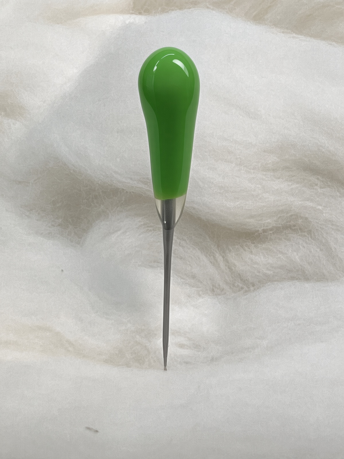 Felt Alive green single felting needle with glossy teardrop handle on natural wool