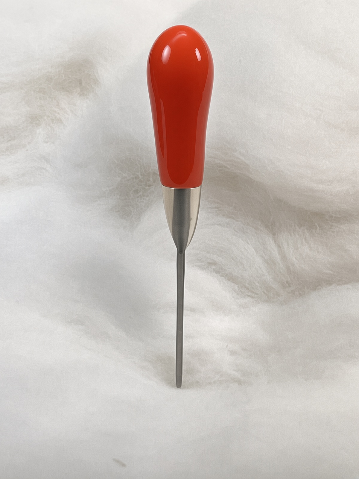 Felt Alive orange single felting needle with glossy teardrop handle on wool