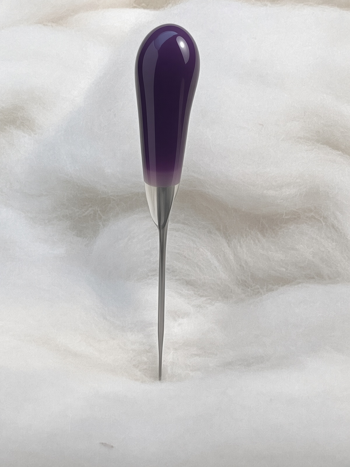 Felt Alive purple single felting needle with glossy teardrop handle on wool